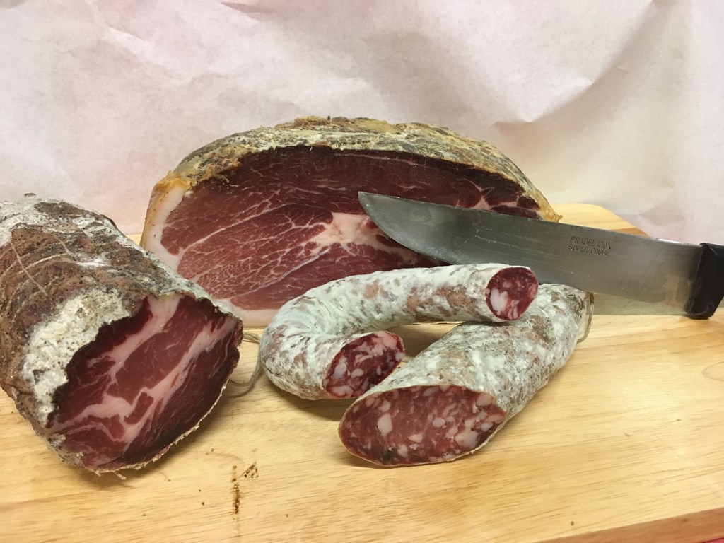 Charcuterie artisanale Le-raygal-charcuterie sur planche en bois dans le Tarn, jambon sec et saucissons tranchés