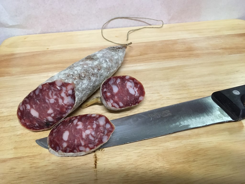 Saucisson sec tranché sur planche en bois, spécialité artisanale Le-raygal-charcuterie dans le Tarn